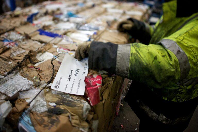 Un agent de tri pose une tiquette sur une balle d'emballages cartons. Elle sert  indiquer la matire et le jour de production de la balle.